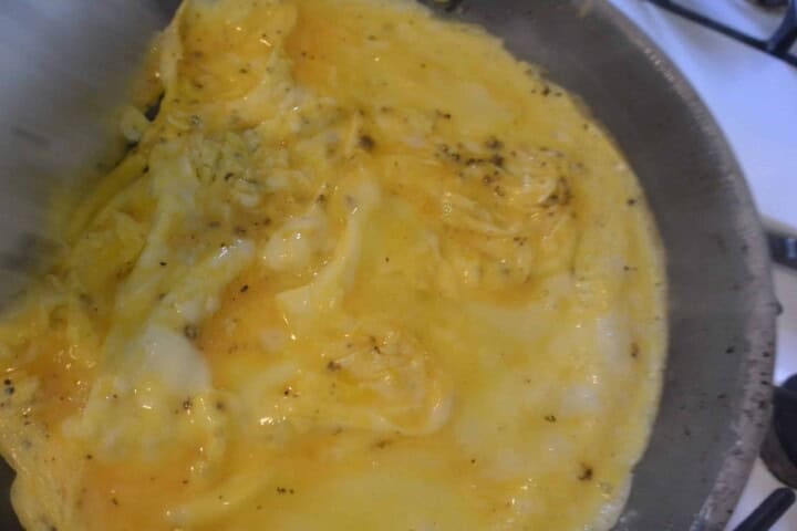 An omelet being cooked in a pan on the stove