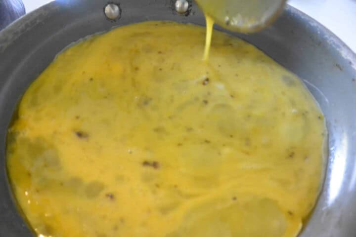 A pan with Eggs being poured into it