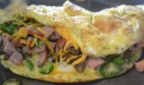 An omelet with meat and vegetables on top of a pan