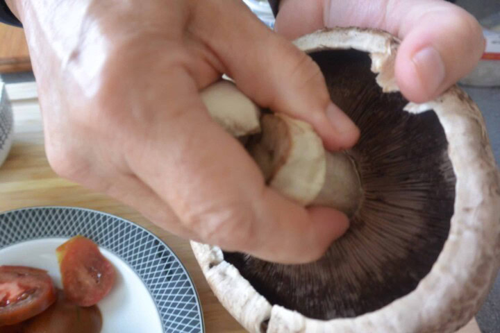 A person is removing the stem from a mushroom