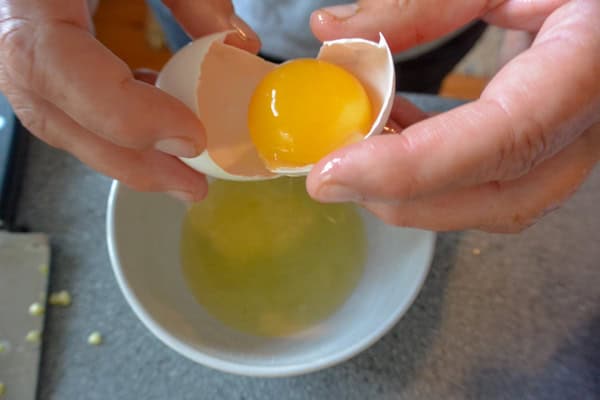 A person is holding an egg in a bowl