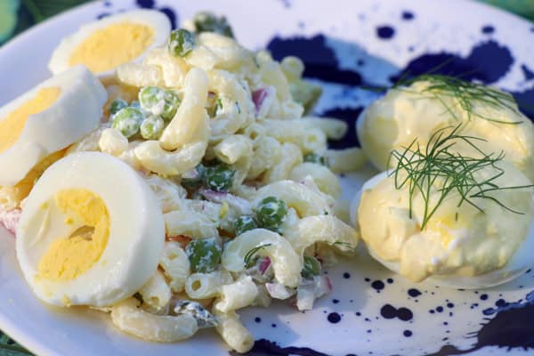 A plate with a macaroni salad and two hard boiled eggs