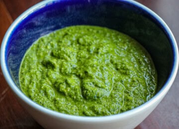 A bowl of green pesto on a table