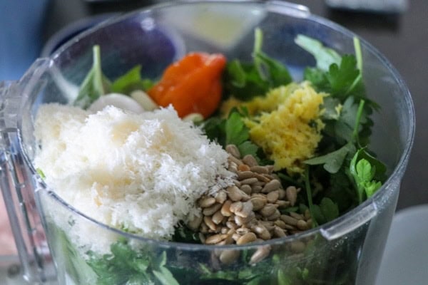A blender filled with greens, nuts and seeds