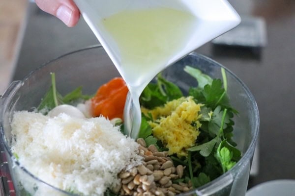 A blender filled with greens, nuts and seeds