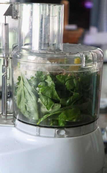 A food processor with basil in it