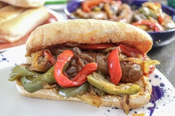 A sausage sandwich with peppers and onions on a plate