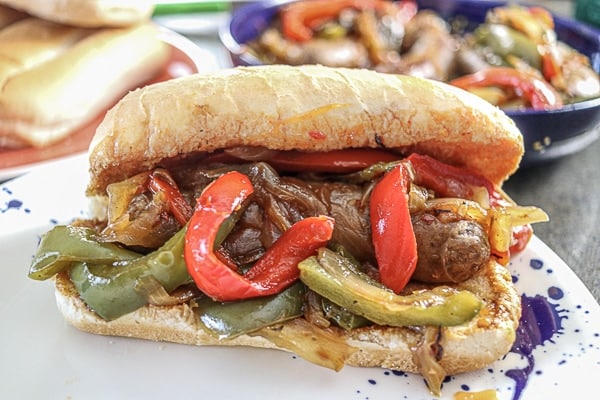 A sausage sandwich with peppers and onions on a plate