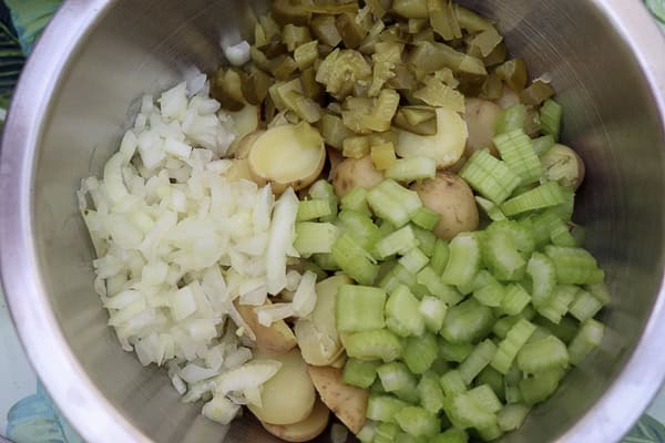 A bowl of chopped vegetables including onions, celery, and potatoes
