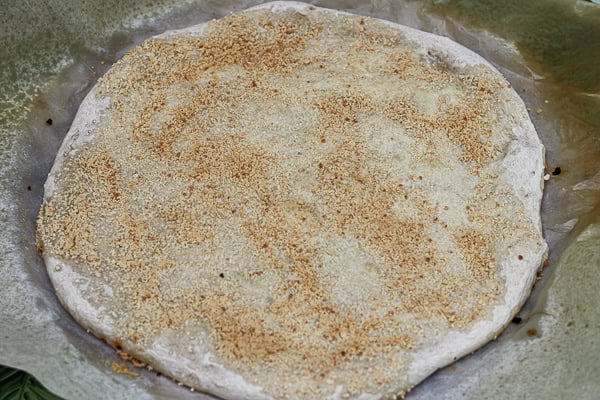 A pizza with a crust on top sitting on a paper