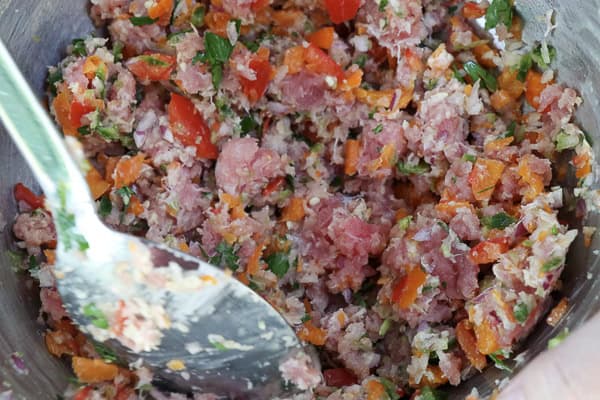 A bowl of tuna and spices with a spoon