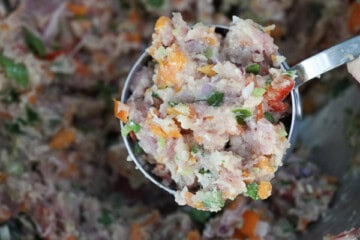 A person is scooping out a cup of tuna cake mixture