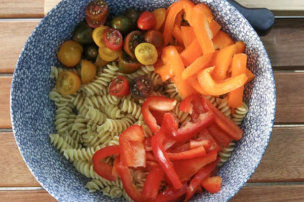 A bowl of pasta with red peppers and tomatoes