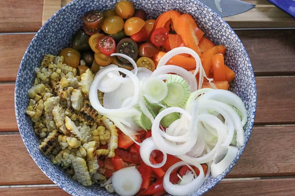 A bowl of vegetables with onions, peppers, and corn