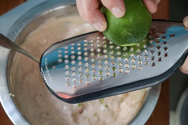 A person grating a lime on a grater