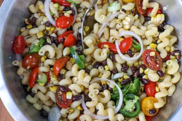 A bowl of pasta salad with tomatoes, corn, and black beans