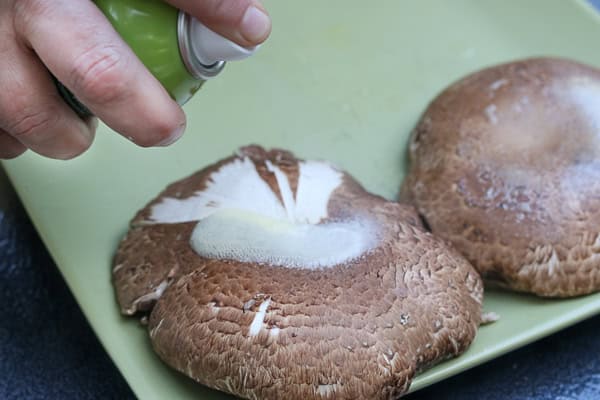 A person is using a spray to spray on mushrooms