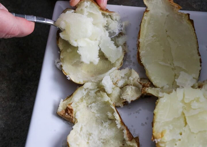 Baked potato skins. Scooping out potatoes from the potato skin