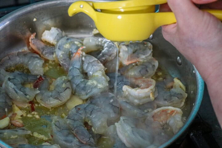 Lemon squeezed into Shrimp Scampi  in pan