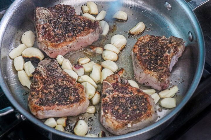 Herb crusted lamb chops with garlic cloves in a pan
