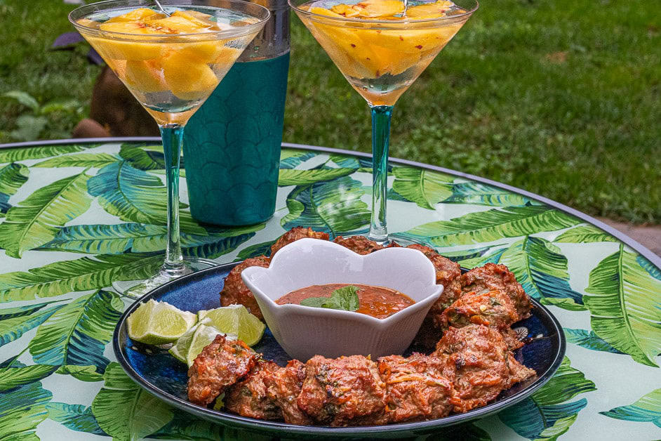 Meatballs on a plate with dipping sauce and martinis with fruit