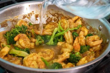 Water added to pan with Shrimp and broccoli in a pan