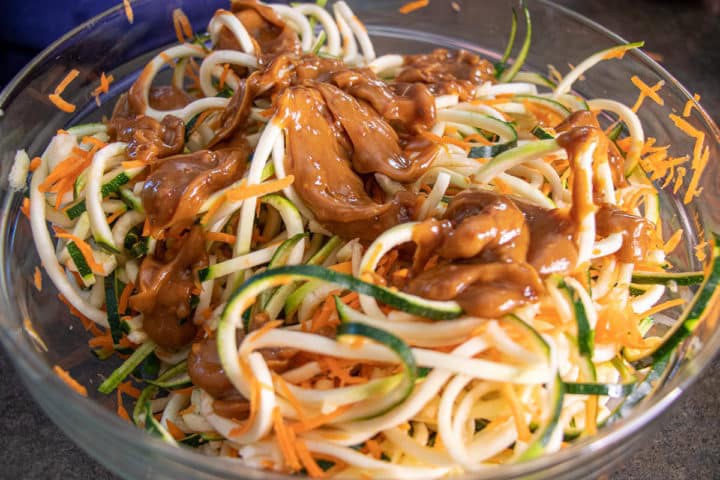 A bowl of noodles with peanut sauce on top