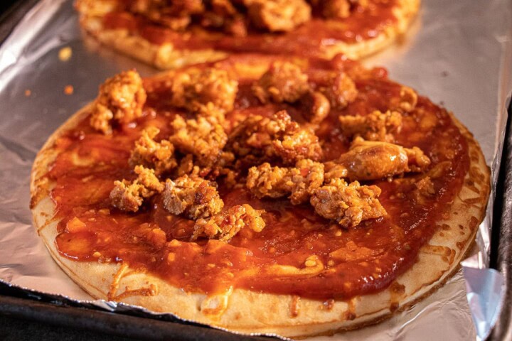 Sauce on pizza crust with sausage