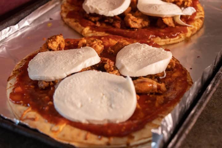 Sauce on pizza crust with sausage and cheese