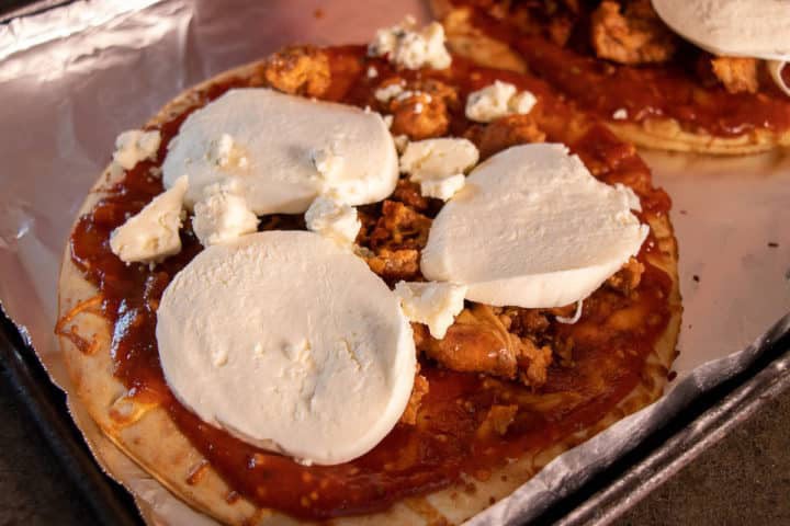 Sauce on pizza crust with sausage and cheese