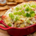 Crab dip topped with green onions in a casserole dish