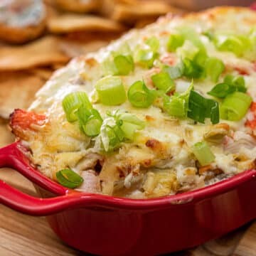 Crab dip topped with green onions in a casserole dish