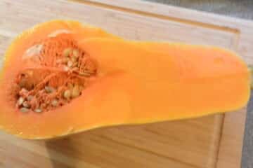 A cut up orange squash sitting on a cutting board