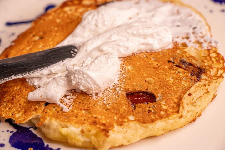 A plate with a pancake and whipped cream on it