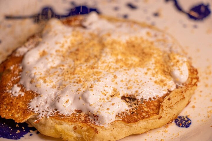 A plate with a pancake and whipped cream on it