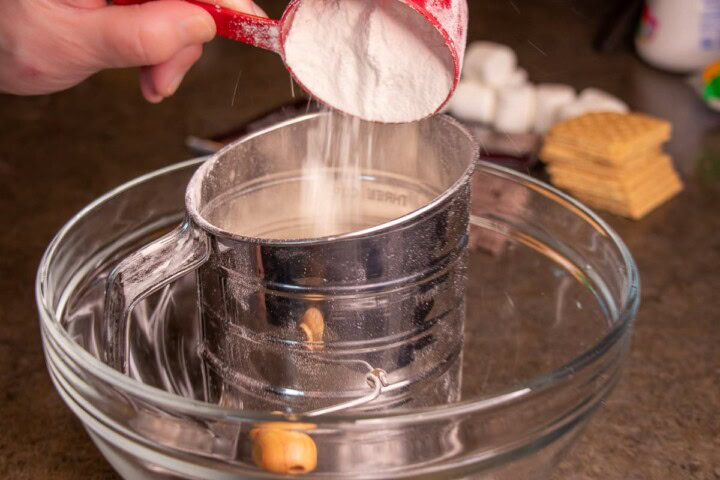 Someone pouring sugar into a bowl with a spoon