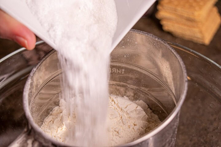 A person pouring flour into a bowl