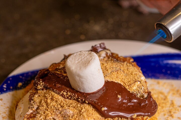 A person is holding a marshmallow on top of a dessert