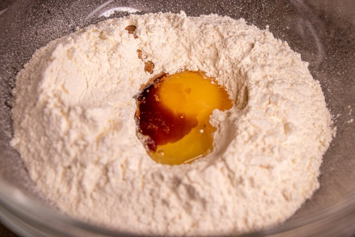An egg is in a bowl of flour and sugar