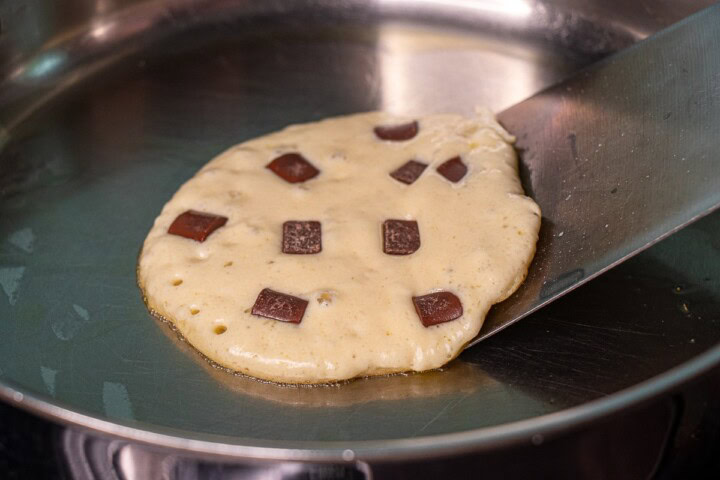 A cookie is being cooked in a pan with chocolate chips