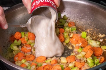 Creamy of mushroom soup poured in apan with carrots, celery and onion