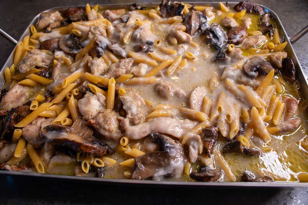 Chicken, mushrooms, pasta and sauce in roasting pan